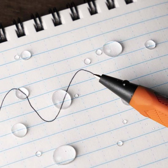 Oranje pen met zwarte punt schrijft een gebogen lijn op een notitieboekje met blauwe lijnen en waterdruppels.