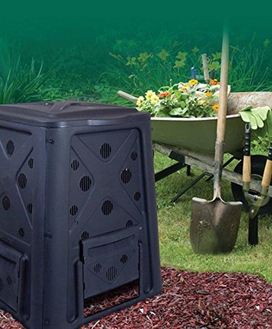 Zwarte compostbak naast een kruiwagen vol met bloemen en tuingereedschap.