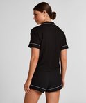 Vrouw in zwart pyjamashirt met witte bies, vanaf de achterkant.