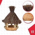 Detailopname van het rieten dak en de ruwe bast van het houten vogelhuisje.