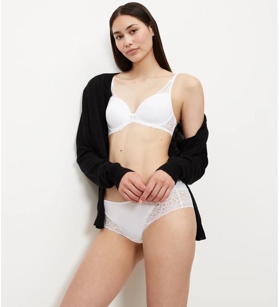 Model draagt witte beha met kant en wit kanten broekje met zwarte cardigan