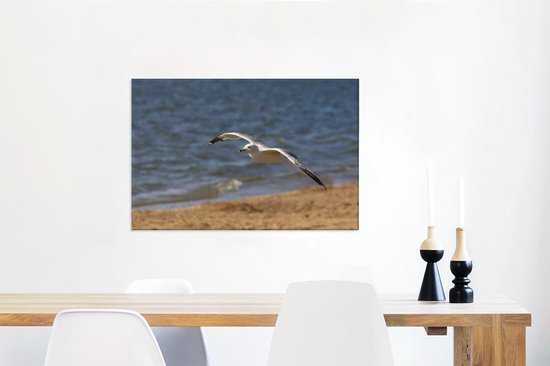 Canvas Schilderij Ringsnavelneeuw vliegt over het strand - 90x60 cm - Wanddecoratie