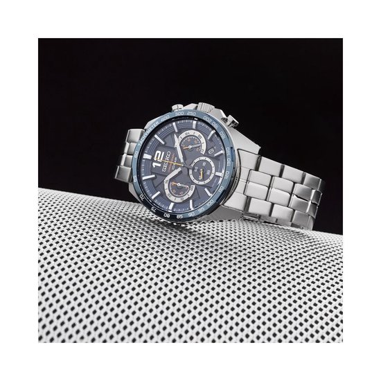 Seiko chronograaf horloge met blauwe wijzerplaat, zilverkleurige kast en band, op een zilverkleurig rooster.