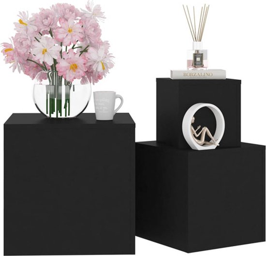 Twee zwarte kubus bijzettafels met decoraties; een vaas met bloemen, een mok en een beeldje.