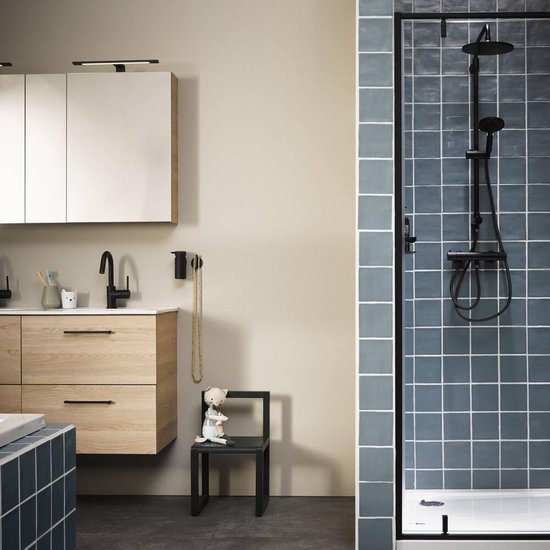 Salle de bain avec meuble-lavabo en bois, robinet noir et douche avec carrelage bleu.