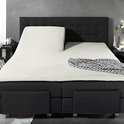 Verstelbaar creme splittopper hoeslaken op een donkergrijs bed.