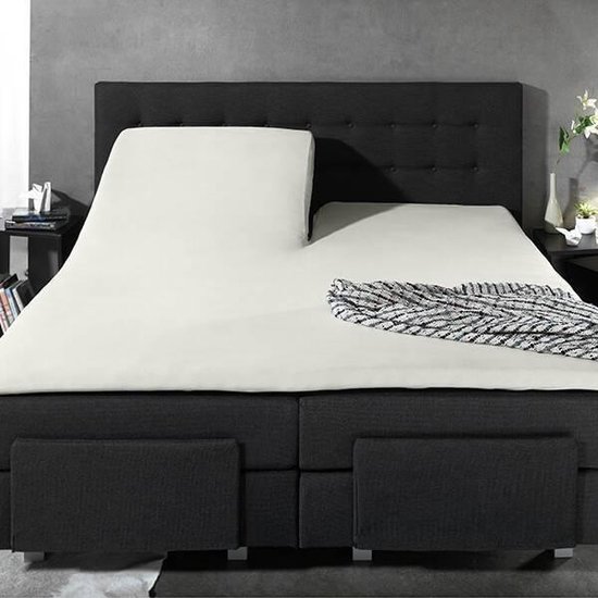 Verstelbaar creme splittopper hoeslaken op een donkergrijs bed.