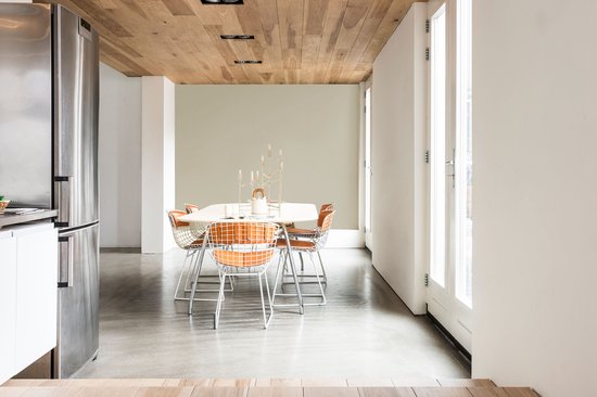 Eetkamer met een ronde tafel met oranje stoelen, een koelkast en een houten plafond.