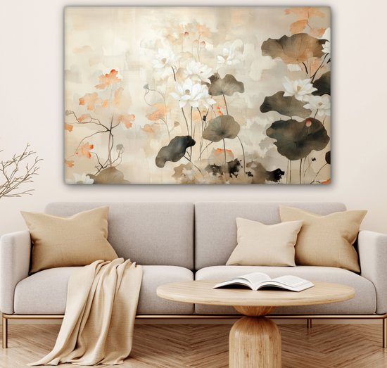 Lichte woonkamer met een canvasprint van witte lotusbloemen en bruine bladeren, boven een grijze bank met kussens.