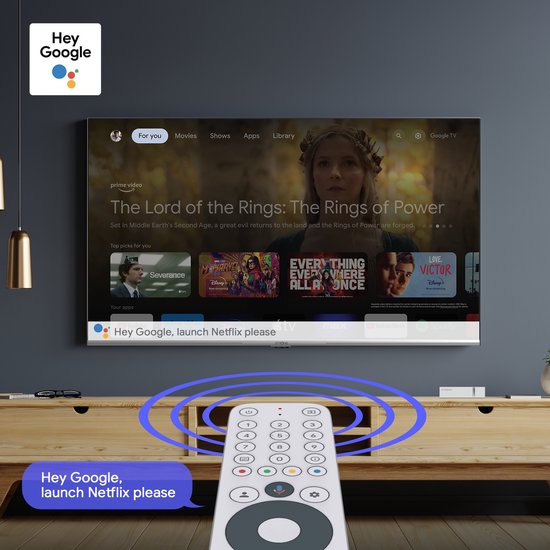 Een persoon bedient een tv met een afstandsbediening en de Google Assistent.