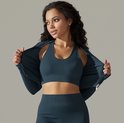 Model dat een blauwgrijze sportbeha met ribbeltextuur en een opengeritste jas met lange mouwen draagt.