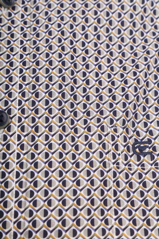Close-up van de stof van een overhemd met een geometrisch patroon in blauw, wit en geel. Een opgestikte borstzak met logo.
