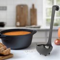 Grijze soeplepel in kattenvorm naast een pan met soep, brood en pompoen.