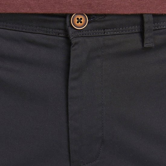 Detail van de knoopsluiting van een zwarte chino.