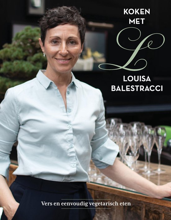 Een glimlachende vrouw met kort bruin haar, gekleed in een lichtblauwe blouse. Ze staat achter een toonbank met wijnglazen.