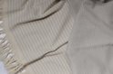 Lichtgrijze hamamdoek met textuur en beige franjes, opgevouwen.