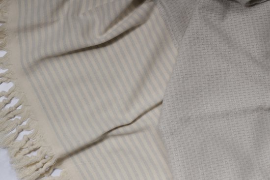 Lichtgrijze hamamdoek met textuur en beige franjes, opgevouwen.