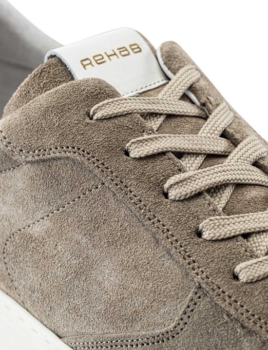 Close-up van een taupe suède sneaker, focus op de veters en Rehab logo op de tong.