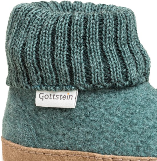 Detail van petrolblauwe, wollen huisslof met gebreide boord en label 'Gottstein'.