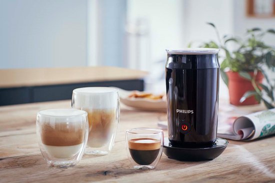Zwarte Philips melkopschuimer met op de achtergrond twee glazen latte macchiato en een klein espresso-kopje.