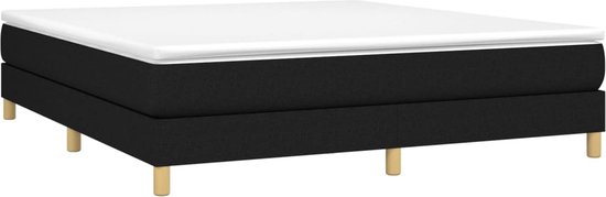 Zwart boxspringbed met een wit matras en houten pootjes.