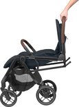 Donkerblauwe Maxi-Cosi kinderwagen met bruine handvatten, wordt door een hand ingeklapt.