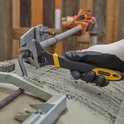 Gloved hand gebruikt Stanley verstelbare moersleutel op gebogen metalen staaf. Zwart en geel handvat.