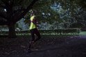 Vrouw in het donker joggend met een fluoriserend geel hesje met roze accenten.