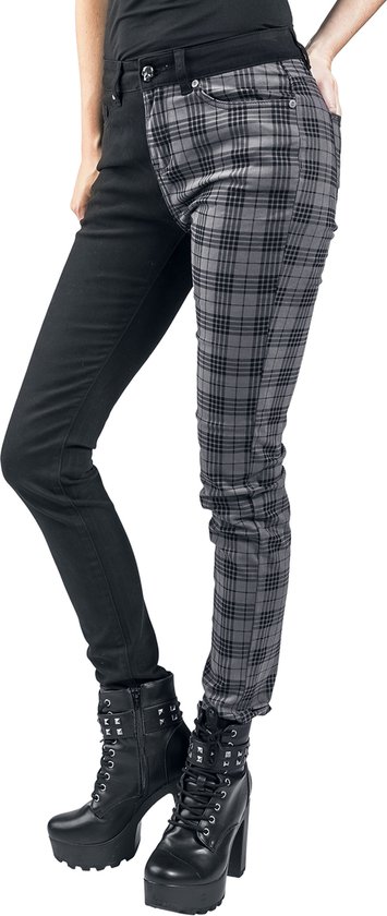 Model draagt een broek, zwart aan de linkerzijde en met een grijze ruit aan de rechterzijde. Zwarte enkellaarsjes met gespen en plateauzool.