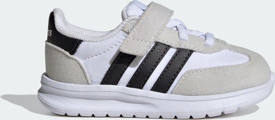 Witte kindersneaker met grijze suède overlays, zwarte Adidas-strepen en klittenbandsluiting.