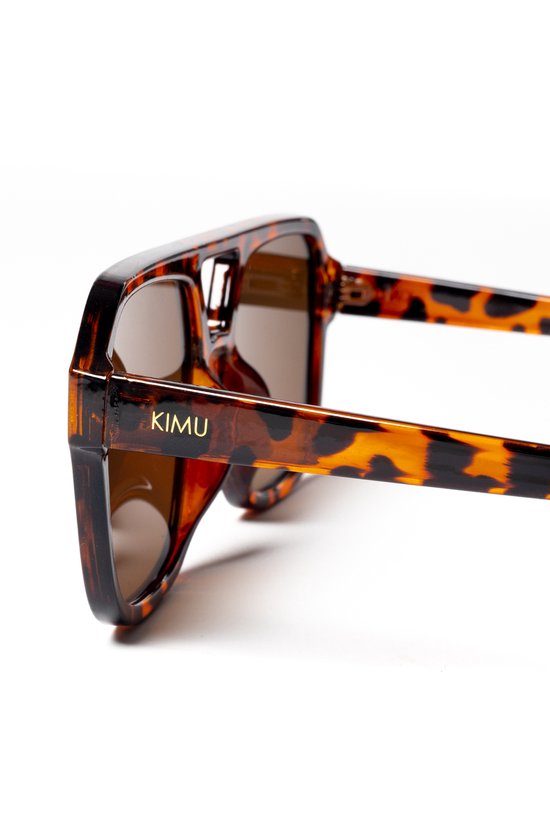 Détail de la monture écaille de tortue des lunettes de soleil avec logo 'KIMU'.