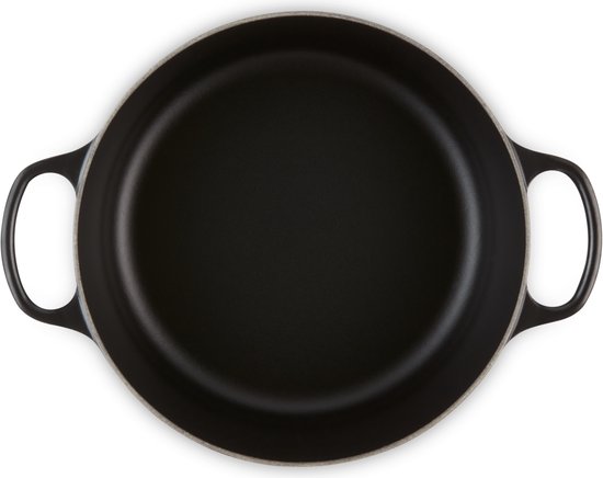 Bovenaanzicht van een zwarte, ronde gietijzeren koekenpan met twee handvatten.