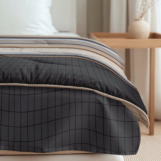Detail van een dekbed op een bed, met een grafische print van zwarte ruitjes en beige, bruine en grijze strepen.