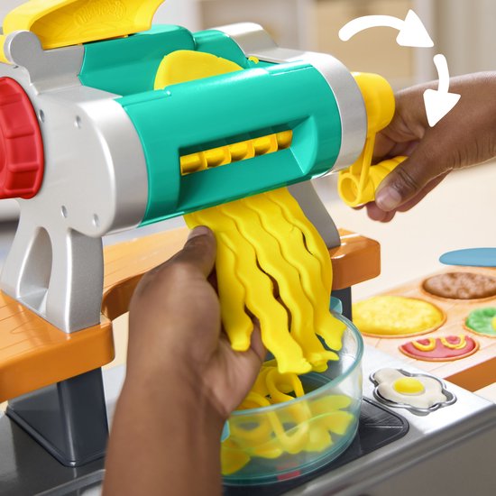 Close-up van Play-Doh pasta die uit de machine komt in een kom.