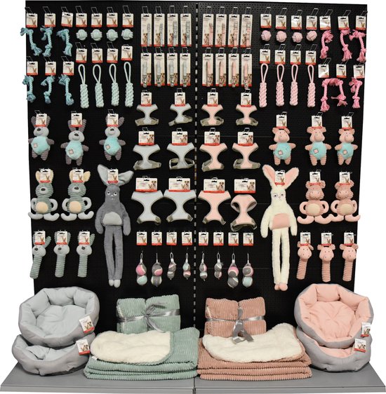 Wandpresentatie met diverse hondenartikelen, waaronder touwballen in roze en blauw.