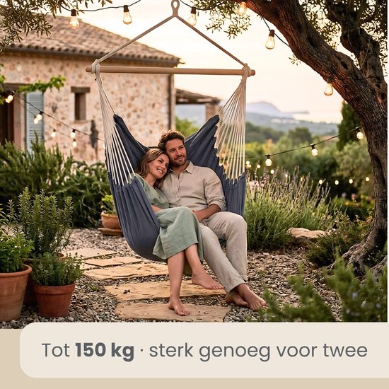 Koppel in een donkerblauwe hangstoel met uitzicht op een tuin bij zonsondergang.