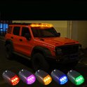 Vierdelige set kleine zonne-ledlampen in rood, paars, oranje en blauw, bovenop een oranje terreinwagen.