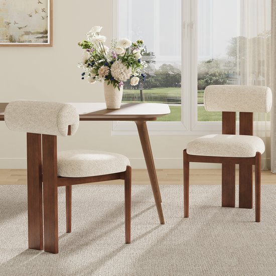 Twee beige eetkamerstoelen met houten frame met zicht op een parklandschap door een raam.