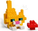 Een LEGO-kat in het geel met blauwe ogen, een roze snuit en een witte snuit, naast een rode paddenstoel.