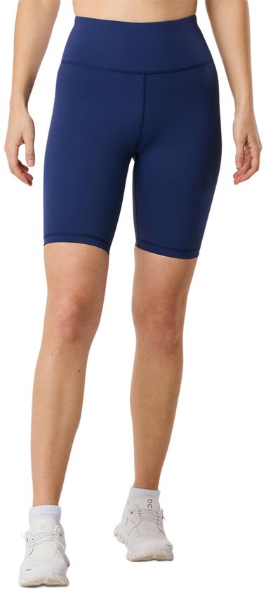 Een vrouw van de voorkant in een donkerblauwe fietsbroek.