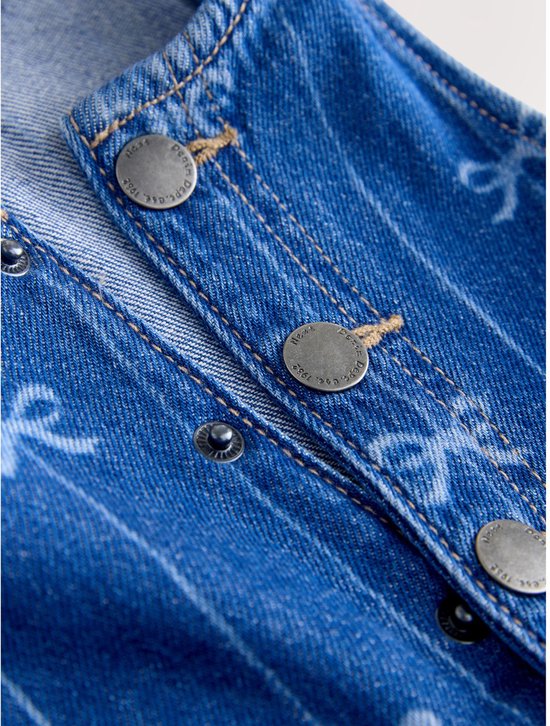 Detail van een blauwe denim jumpsuit met knopen en strikjesprint.