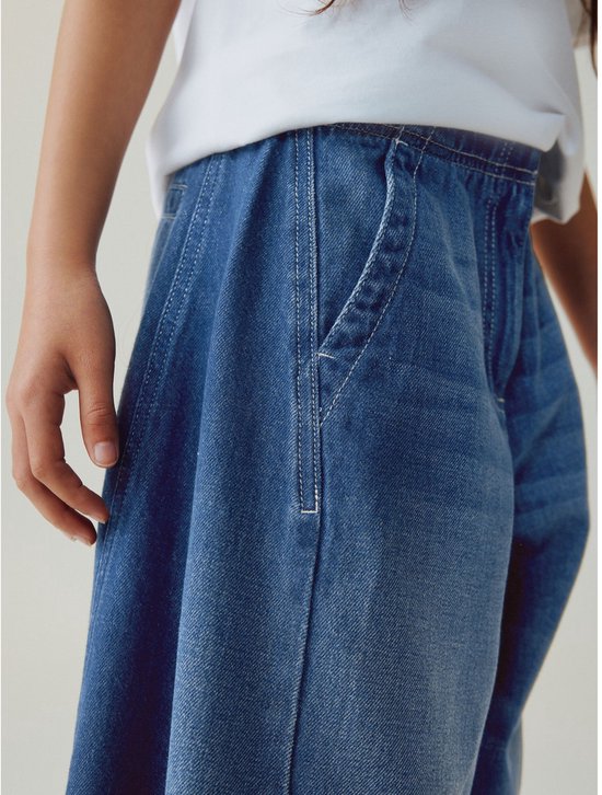 Detail van de zak van een blauwe denim broek gedragen door een meisje.