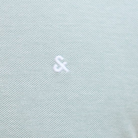 Detail van de kraag van een lichtgroene polo met groen-witte streepjes en witte knopen.