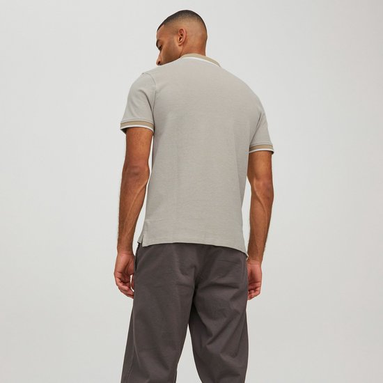 Man draagt de achterkant van een lichtgrijs poloshirt met beige kraag en manchetten met witte bies.