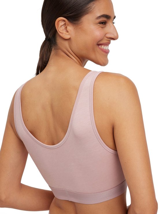 Une femme aux cheveux bruns porte un soutien-gorge Falke rose, photographiée par derrière.