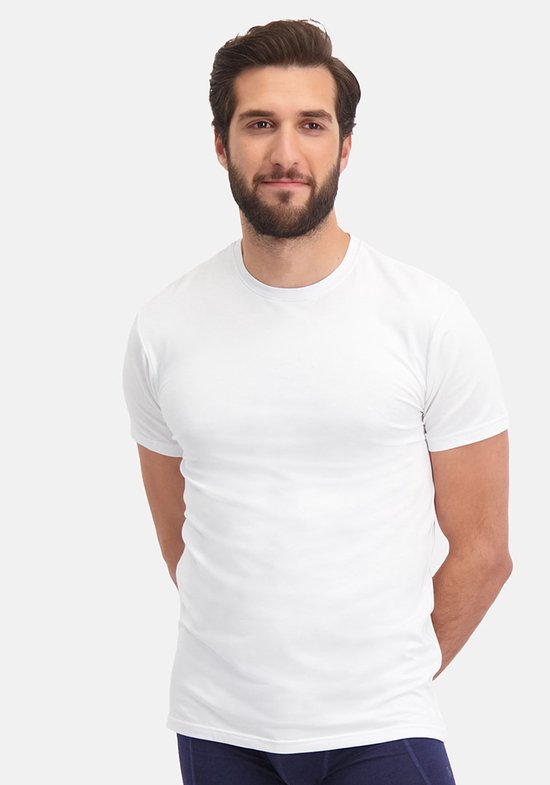 Man met baard en handen achter de rug in een wit T-shirt met ronde hals.