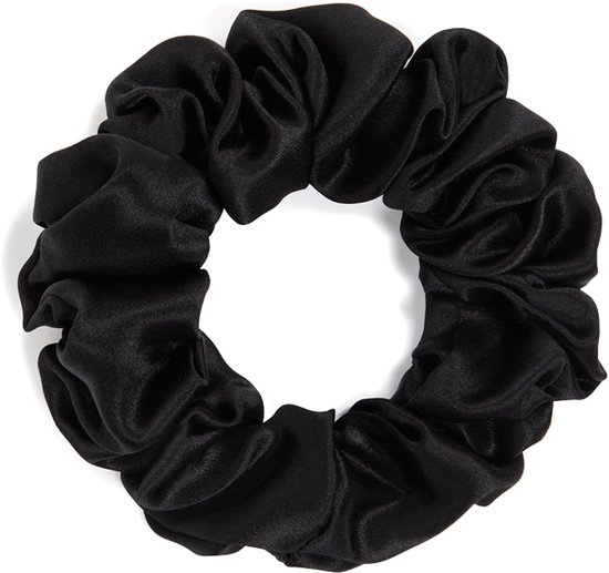 Scrunchie noire en soie texturée, posée sur un fond blanc.