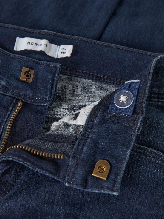Sluiting van een donkerblauwe skinny jeans met drukknoop, ritssluiting en verstelbare tailleband.