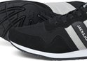 Close-up van een zwarte sneaker met witte en grijze strepen, witte zool en zwarte buitenzool.