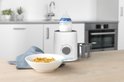 Witte Alecto flessenwarmer met babyfles en kom met babyvoeding op een houten tafel.